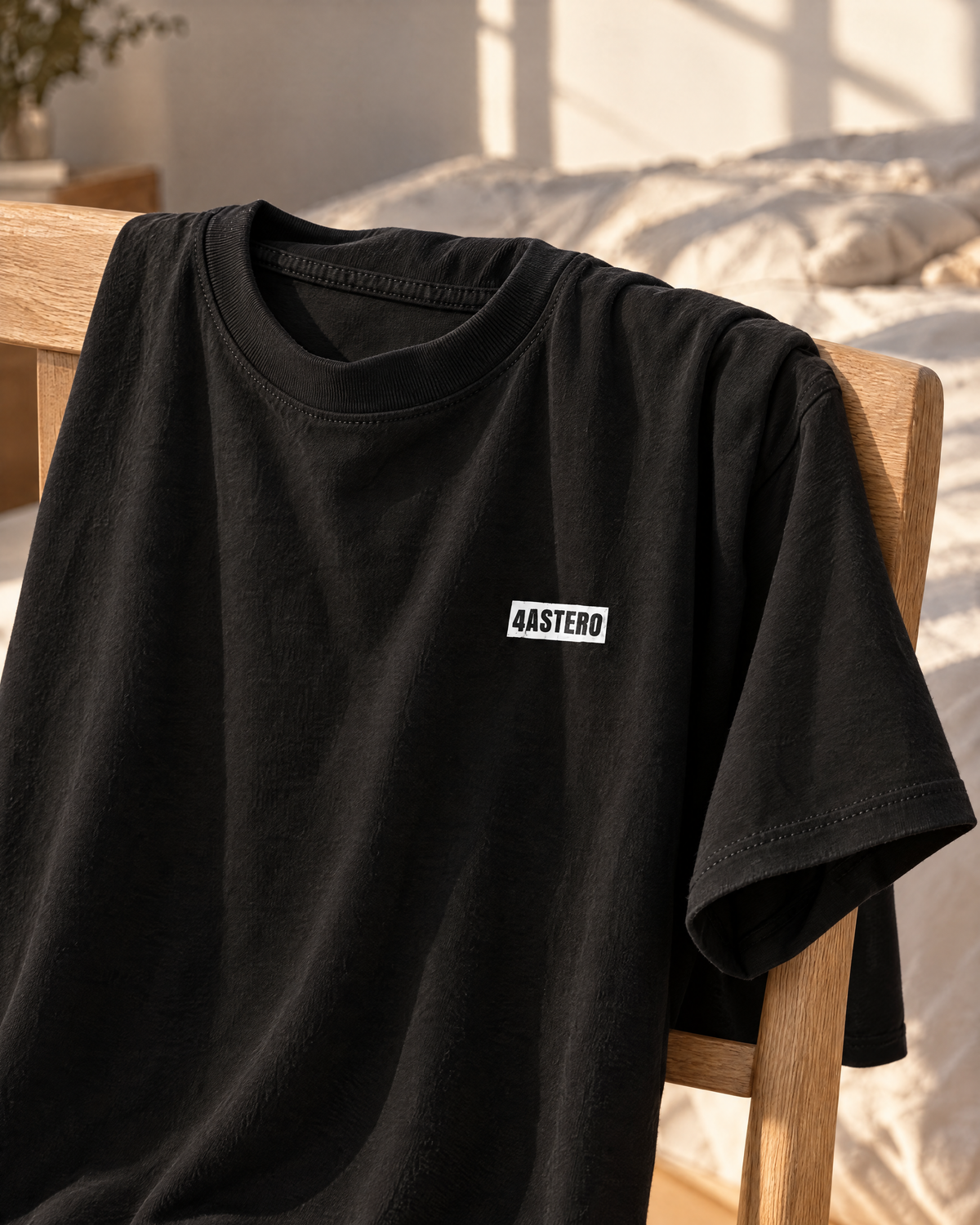 4ASTERO tee in black, front, draped over an oak chair
